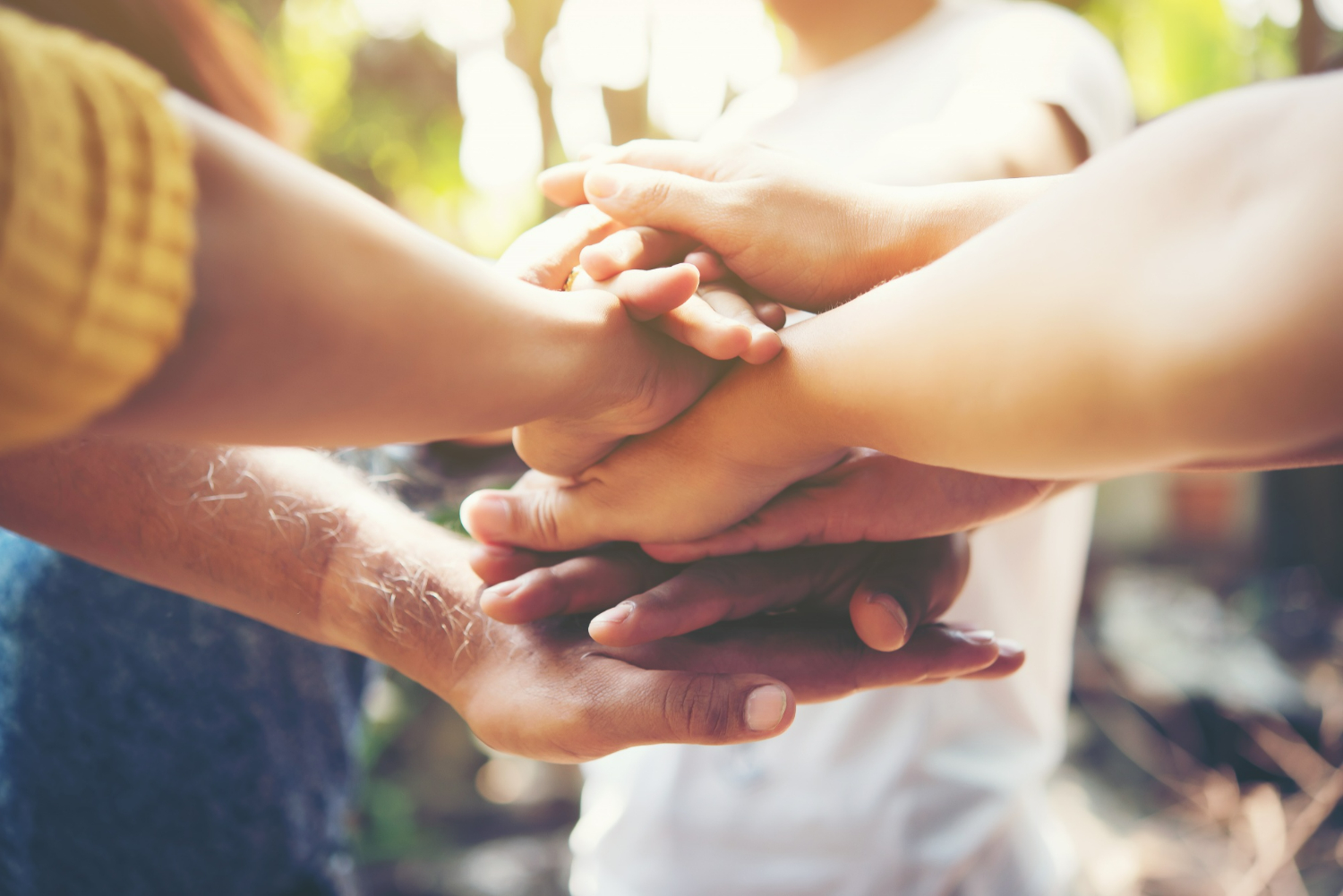 Pessoas felizes com as mãos sob as outras, em busca de líderes do futuro